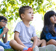 excited-kids-sitting-grass-park-looking-away-together-watching-performance-animators-show-kids-party-friendship-concept